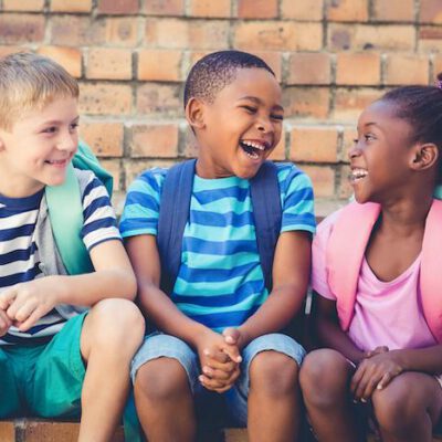 Happy school kids sitting together on staircase at school